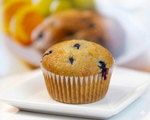 SMART CHOICE Blueberry muffin on a white plate with blurred fruits in the background