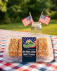 Muffin Town snack loaves in a clear container with American flags on a checkered tablecloth outdoors.